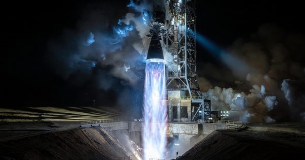 Rocket engine test fire at night showing bright blue-white exhaust plume