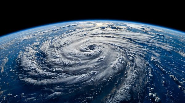 Weather satellite view of a large swirling storm system over ocean seen from geostationary altitude